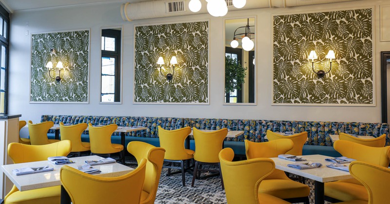 Nicely decorated dining area, long seating booth, tables and yellow chairs