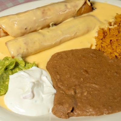 Enchiladas served with refried beans, rice, guacamole, and sour cream.