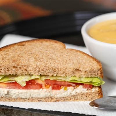 Chicken salad sandwich served with soup.