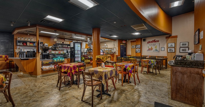 Interior, dining area, tables for two and four with colorful cloths, tile flooring