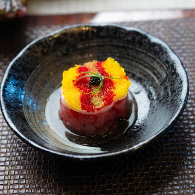 Ahi and Scallop with Tobiko and Caviar served in a black bowl.