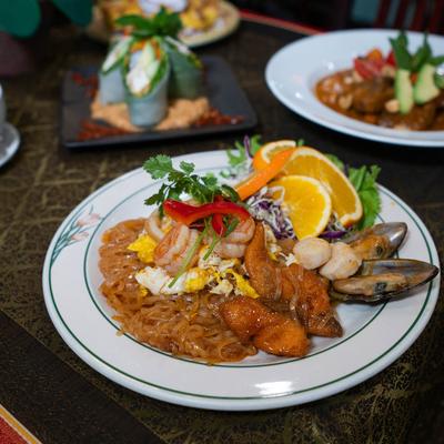 Seafood with noodles plate on a table with assorted food dishes.