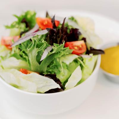 A bowl of vibrant mixed salad with a side of yellow dressing.