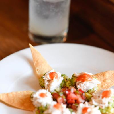 Guacamole tortilla chips appetizer bites  with a cocktail.