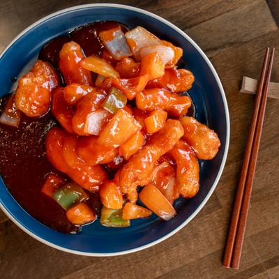 Sweet & Sour Chicken plate on a wooden table with chopsticks, top down view.