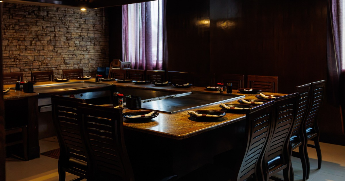 Cozy restaurant dining area with wooden teppanyaki-style table, equipped with a built-in grill