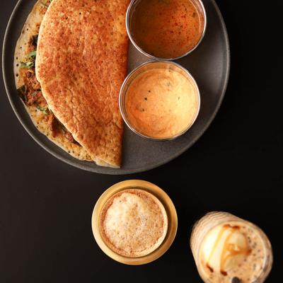 Indian crepe with spicy and tangy chicken, served with condiments.
