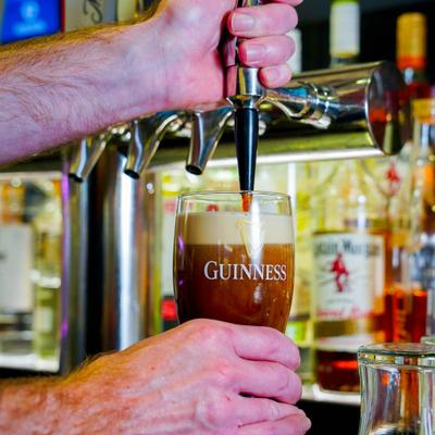 A bartender pouring dark beer from the tap.
