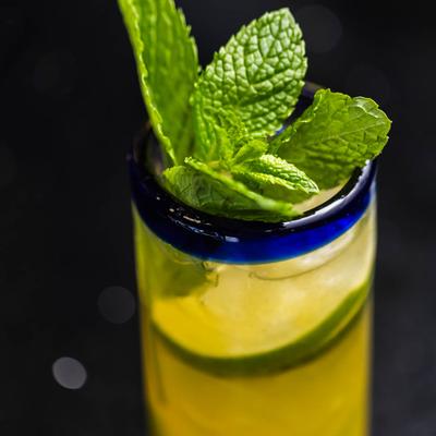 Mojito garnished with cucumber slices and mint sprig, close up.