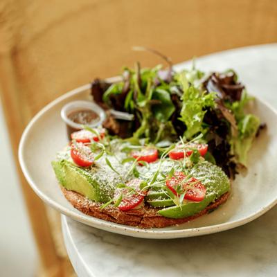 Avocado toast with tomatoes served with mixed greens.