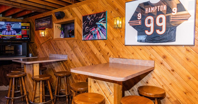 Interior, two tables with bar stools, wall decorations and wall TV screen