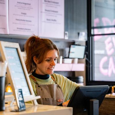 Friendly staffer standing behind cash register screen.