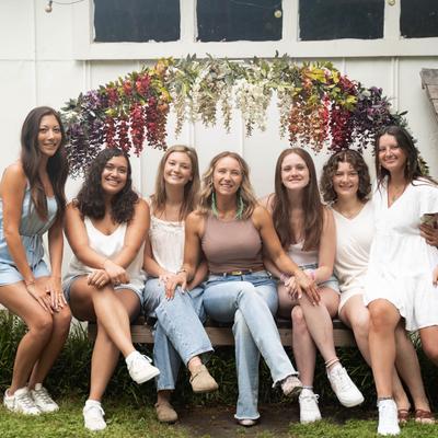 A group sitting on a floral archway bench and smiling at the camera.