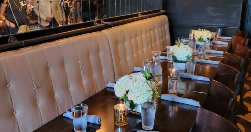 Interior with banquette seating and set tables with flowers