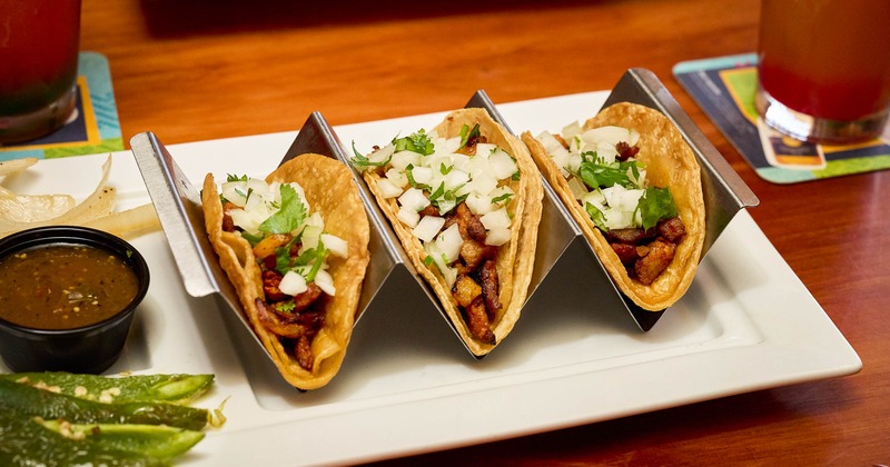 Three tacos topped with onion and cilantro