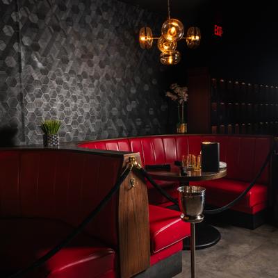Interior featuring red velvet booths, tables and a golden spherical chandelier.