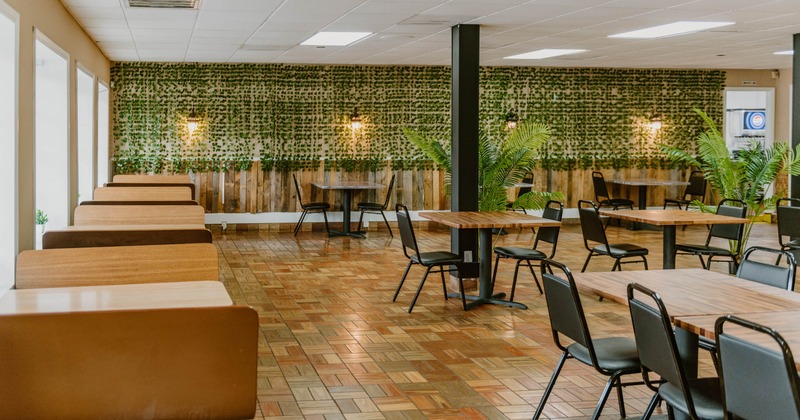 Bright restaurant interior with tables, booth seating, and plants