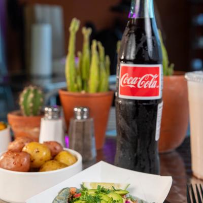 Fish tacos, potatoes and bottle of soda drink.