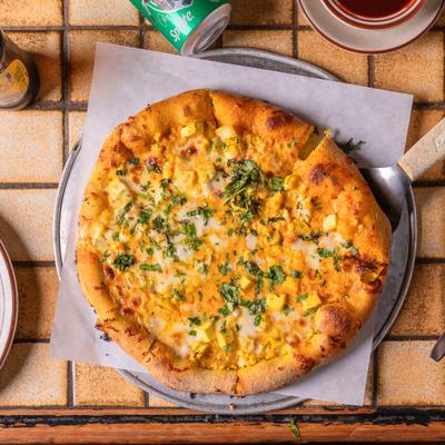 Paneer Masala Pizza on a parchment lined metal plate.