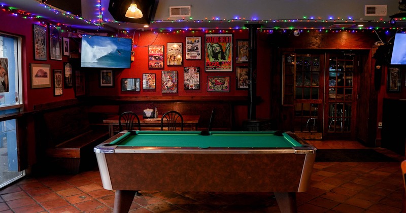 Interior, pool table, wooden banquette benches with chairs and a table, decorated wall