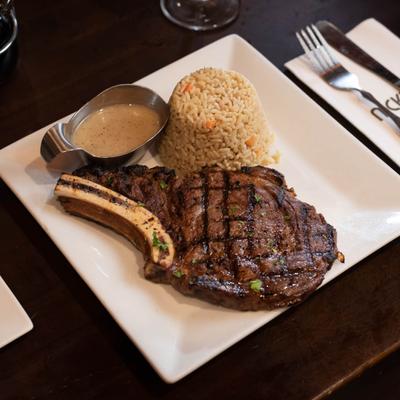 Bone-in rib eye steak with rice and dressing.