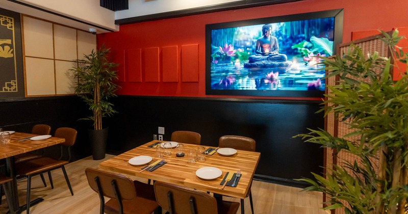 Interior - wooden tables and a large digital artwork of a meditating Buddha on the wall