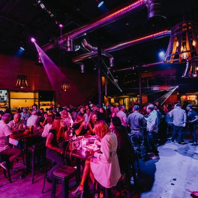 Crowded nightlife venue interior illuminated with colorful party lights.