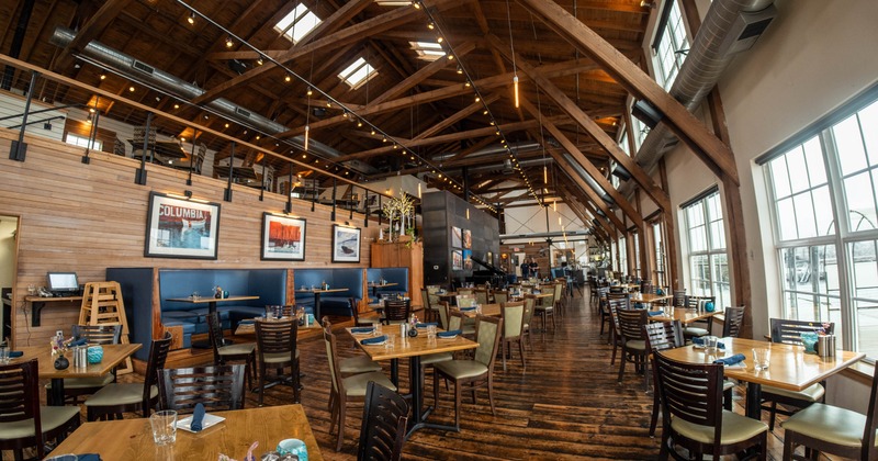 Interior of a rustic, spacious restaurant with wooden decor and large windows