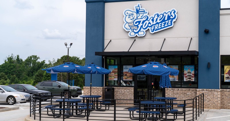 Exterior of a Fosters Freeze restaurant with blue umbrellas and picnic tables