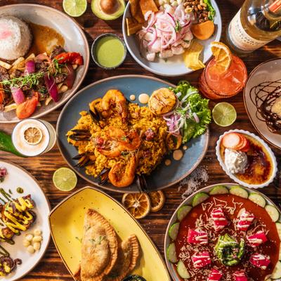 A variety of dishes and drinks displayed across a wooden table, overhead view.