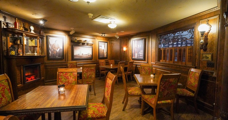 Interior, dining area, wood coated walls with hanged paintings, tables with wooden chairs
