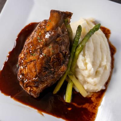 Beef short rib served with mashed potatoes and asparagus.