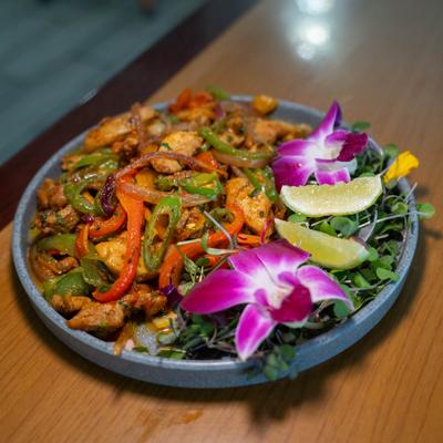 Strips of grilled chicken, bell peppers and onions served with greens and lime.