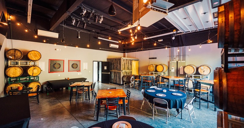 Interior, seating area, concrete flooring, wooden barrels around the room, darts