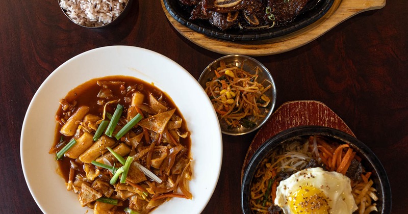 Assorted food dishes including simmered rice cake, grilled short ribs, and pot rice bowl