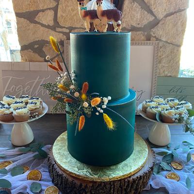 Navy blue wedding cake with floral decoration and two lama figurines on top