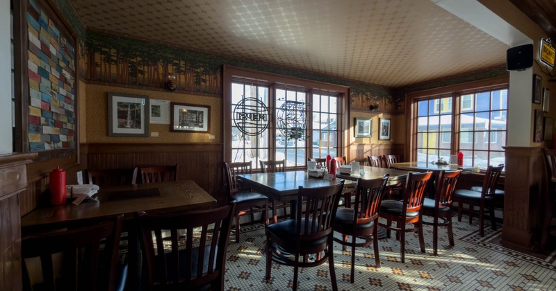 Interior, wide shot of a dining room, wooden top tables with wooden tables, large windows