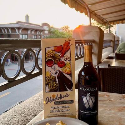 Bottle of red wine served on a outdoor table alongside a menu.
