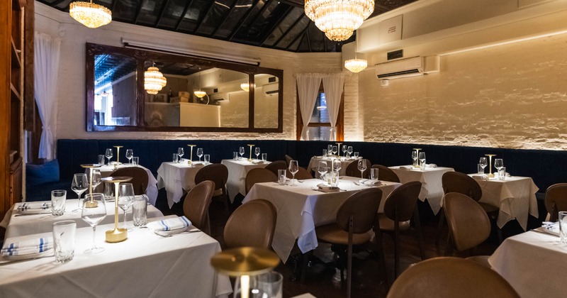An elegant restaurant dining room featuring white tablecloths and chandeliers