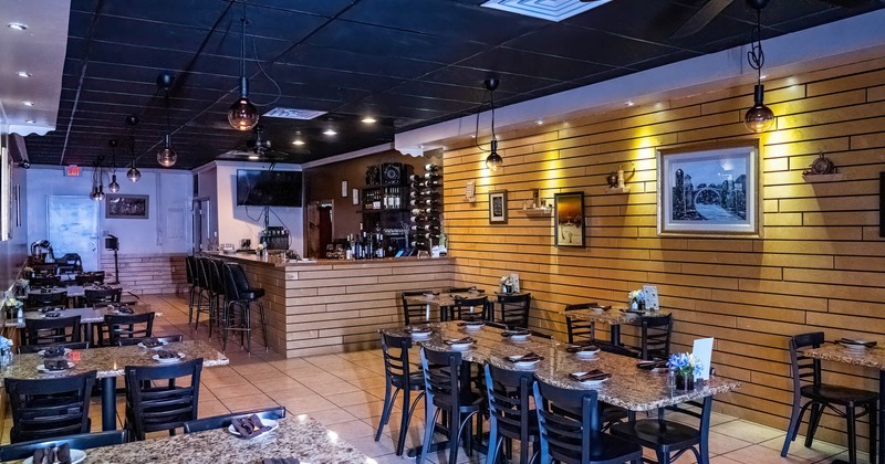 Dining area with a bar in the background, paintings on the walls
