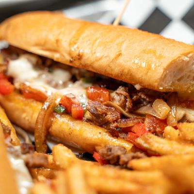 Cheesesteak sandwich served with fries.