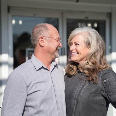 The owners smiling at each other in front of the restaurant.