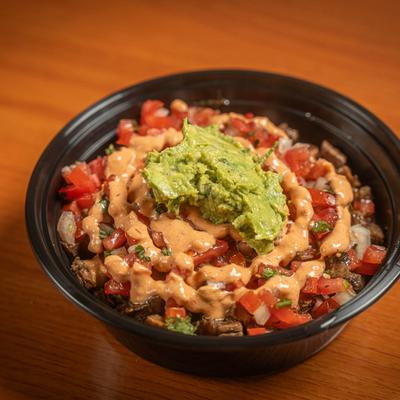A taco bowl topped with Pico, guac, chipotle crema.