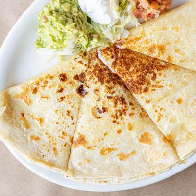 Quesadilla on a plate with guacamole, fresh salsa, and sour cream.
