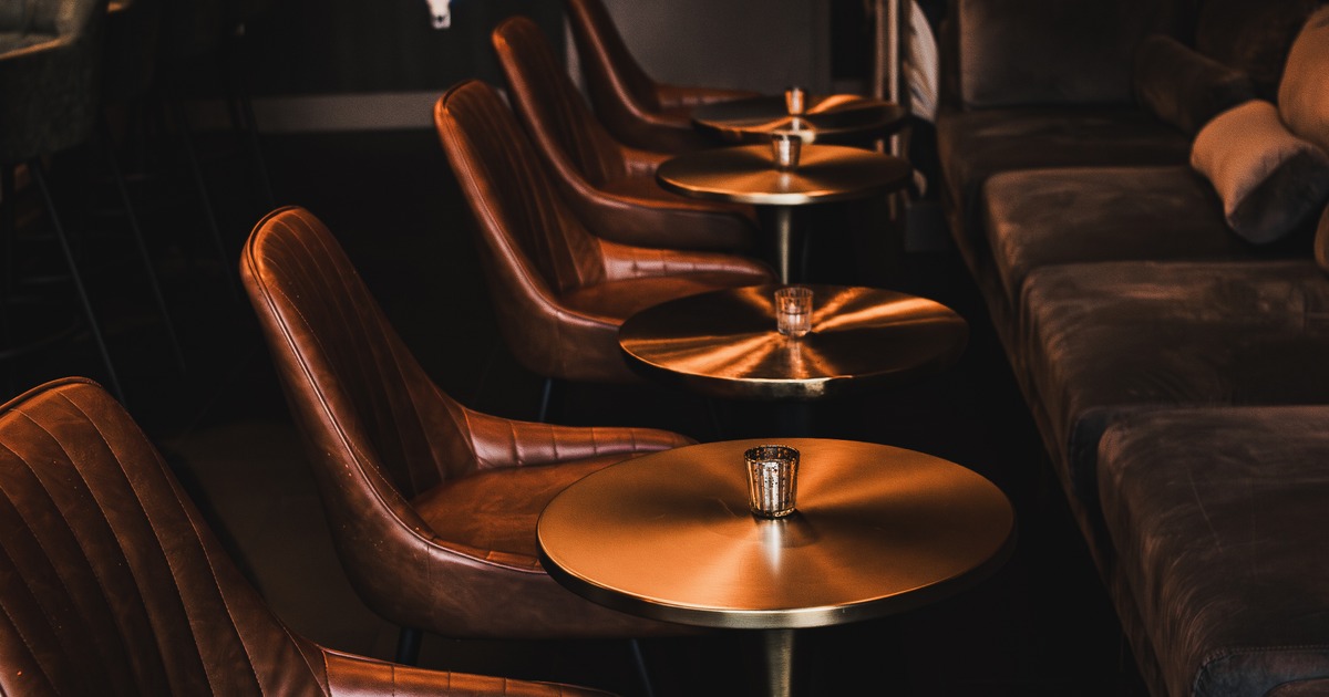 Seating area with brown leather armchairs, metallic tables and a dark sofa