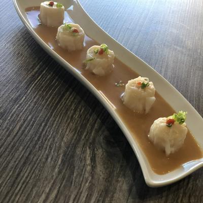 Shrimp dumplings served on a creamy sauce.