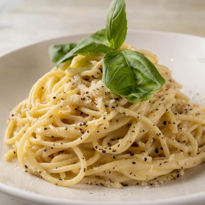 Serving of Cacio E Pepe pasta, garnished with fresh basil.