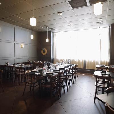 Dining room with set tables, pendant lights, and a large window.