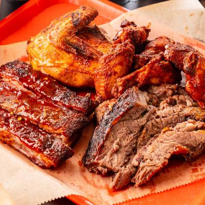 Four meat combo plate with ribs, brisket, chicken, and wings, served with toast.