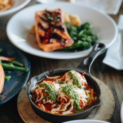 Baked meatballs in a cast iron skilled served on a table with a salmon entree.
